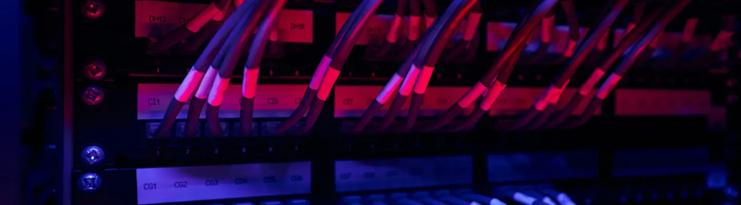 Structured network cabling running into a patch panel in a dark equipment room.